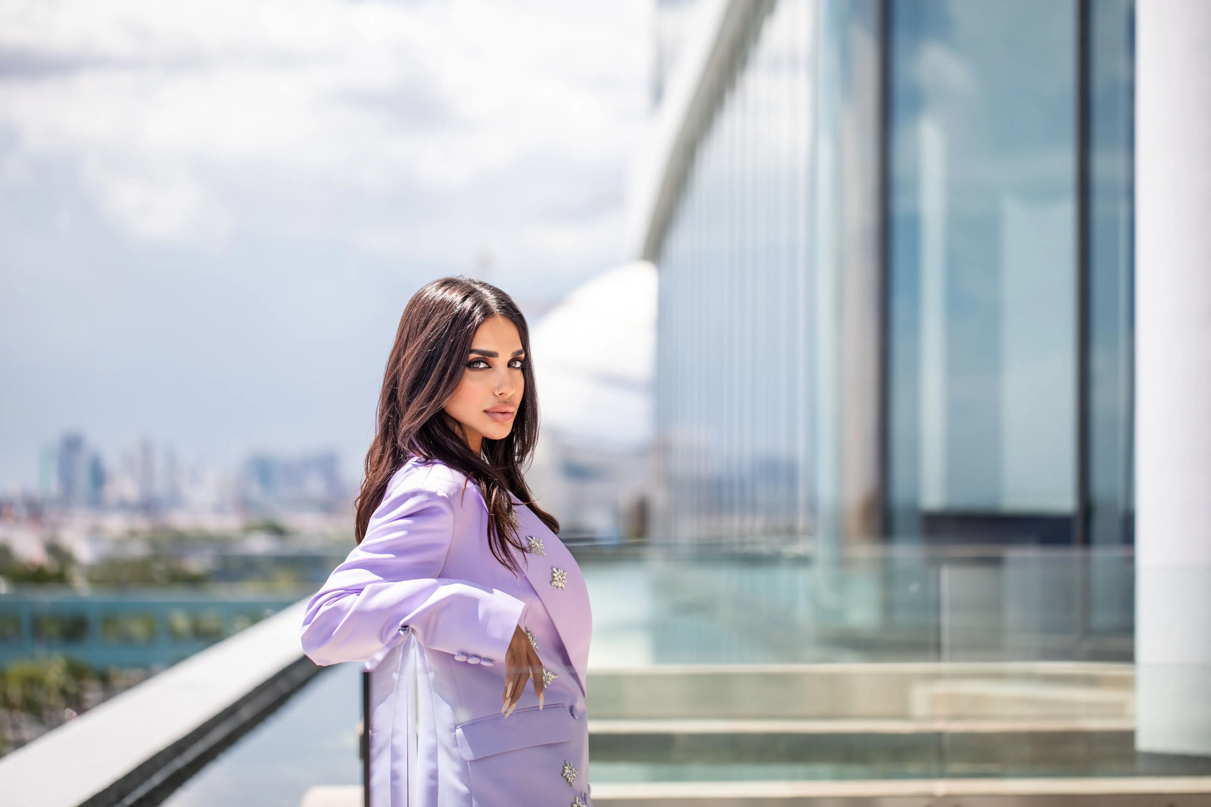 Sara Al Madani in a lavender suit on a balcony