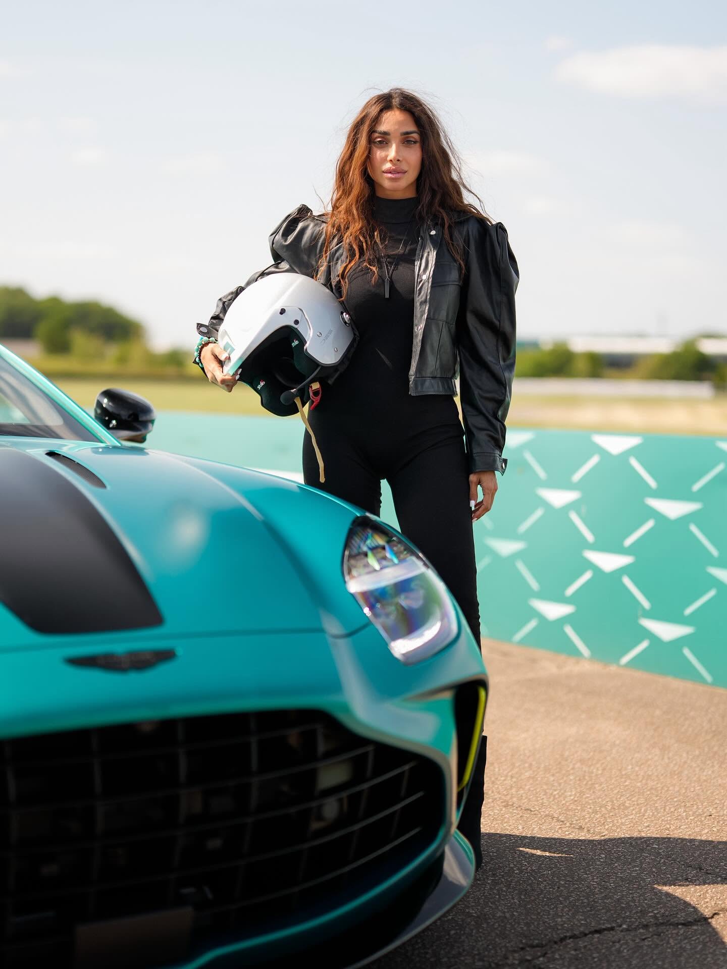 Sara Al Madani beside a sports car holding a helmet